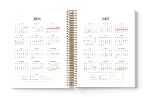 Open planner showing calendar pages for 2026 and 2027 with a gold spiral binding.