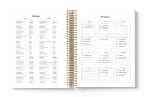 Spiral-bound planner with holiday and birthday lists on a white background